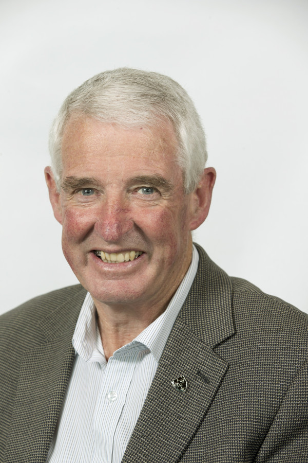 Head and shoulders photo of man wearing a white collared shirt and suit jacket